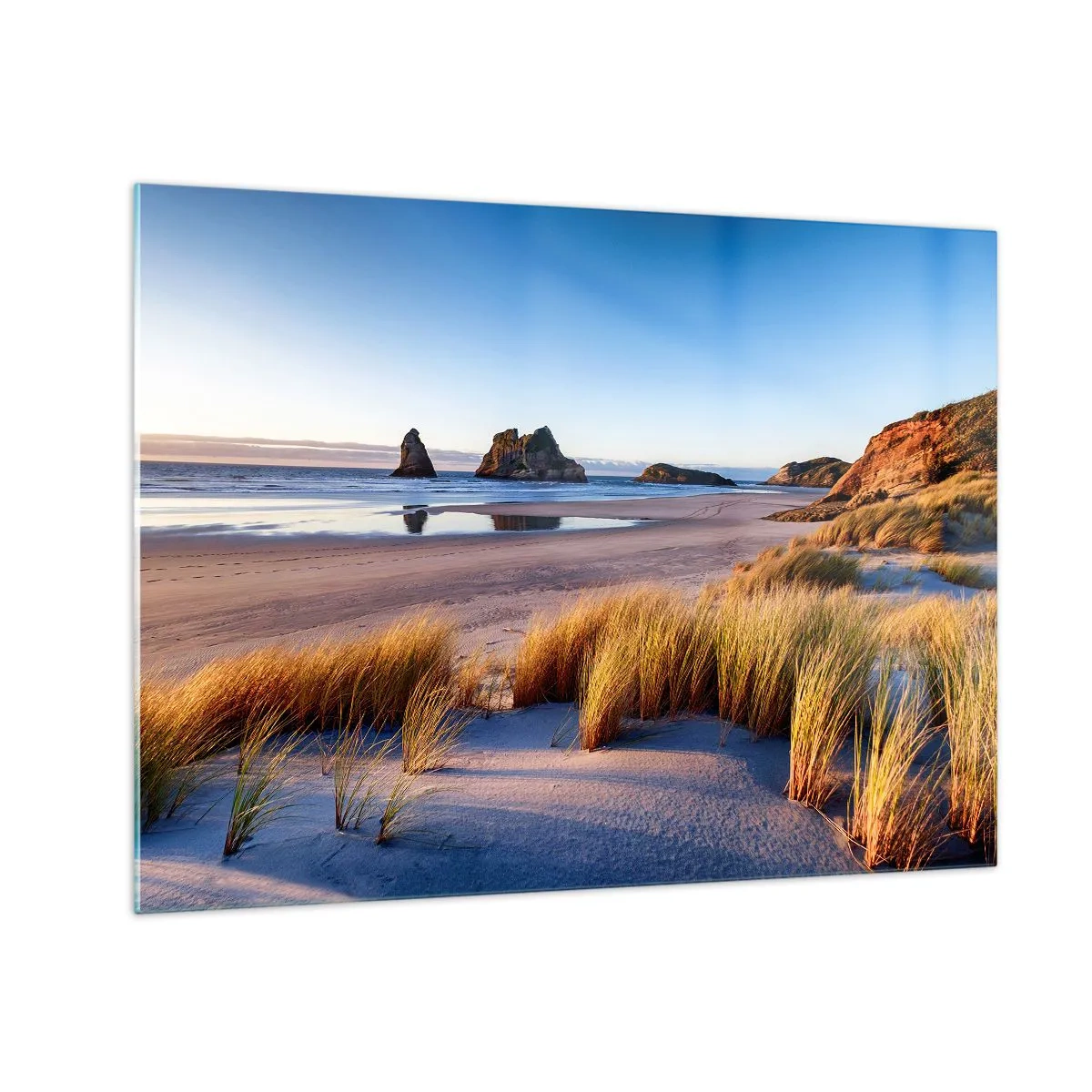 Tablou pe sticlă - O plajă în zori cu iarbă și pietre în fundal și o mare calmă - 70x50cm - Pentru cei care caută pacea - Decorațiune modernă pentru perete pentru living și dormitor ARTTOR